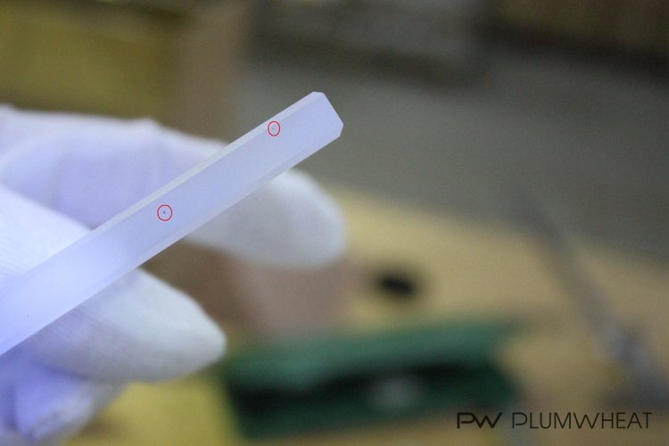 Tiny black dots circled on a 100 x 75 mm LED glass sample during quality inspection in China
