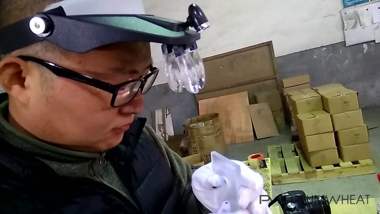 Inspector using a head-mounted magnifier to examine an LED glass component in China