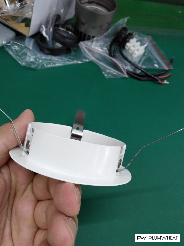 White downlight mounting frame with metal spring clips held for inspection
