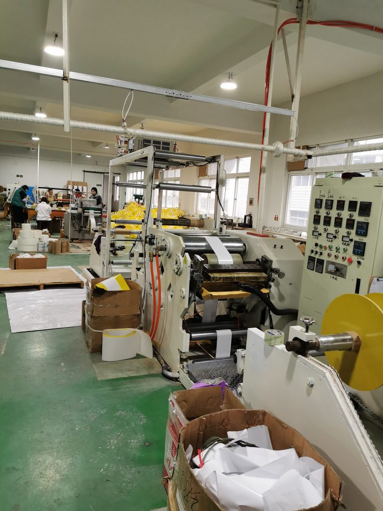 Production equipment and workers inside a fly paper manufacturing workshop in China.